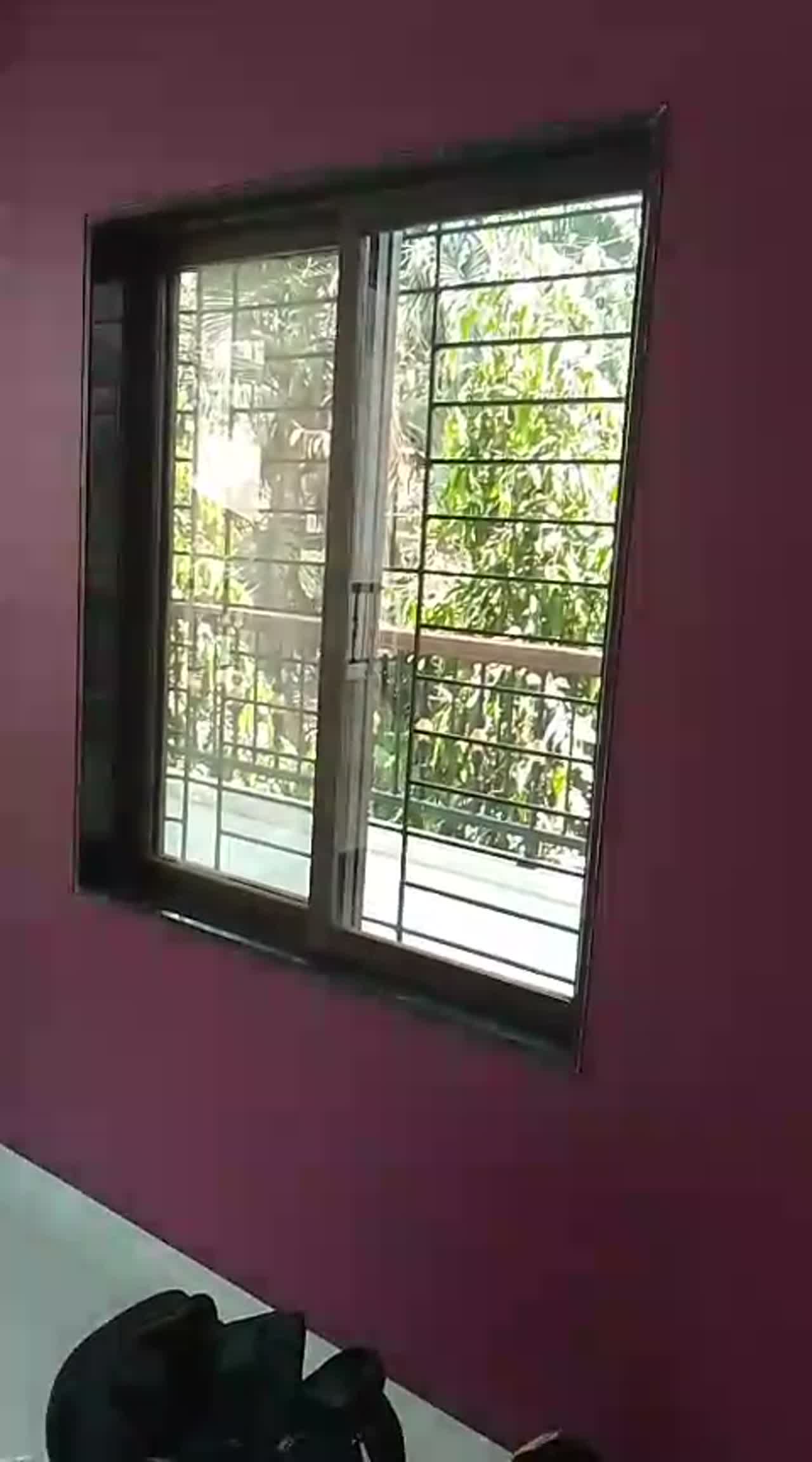 Video of an untreated sliding bedroom window with grille in a purple-walled room before film application