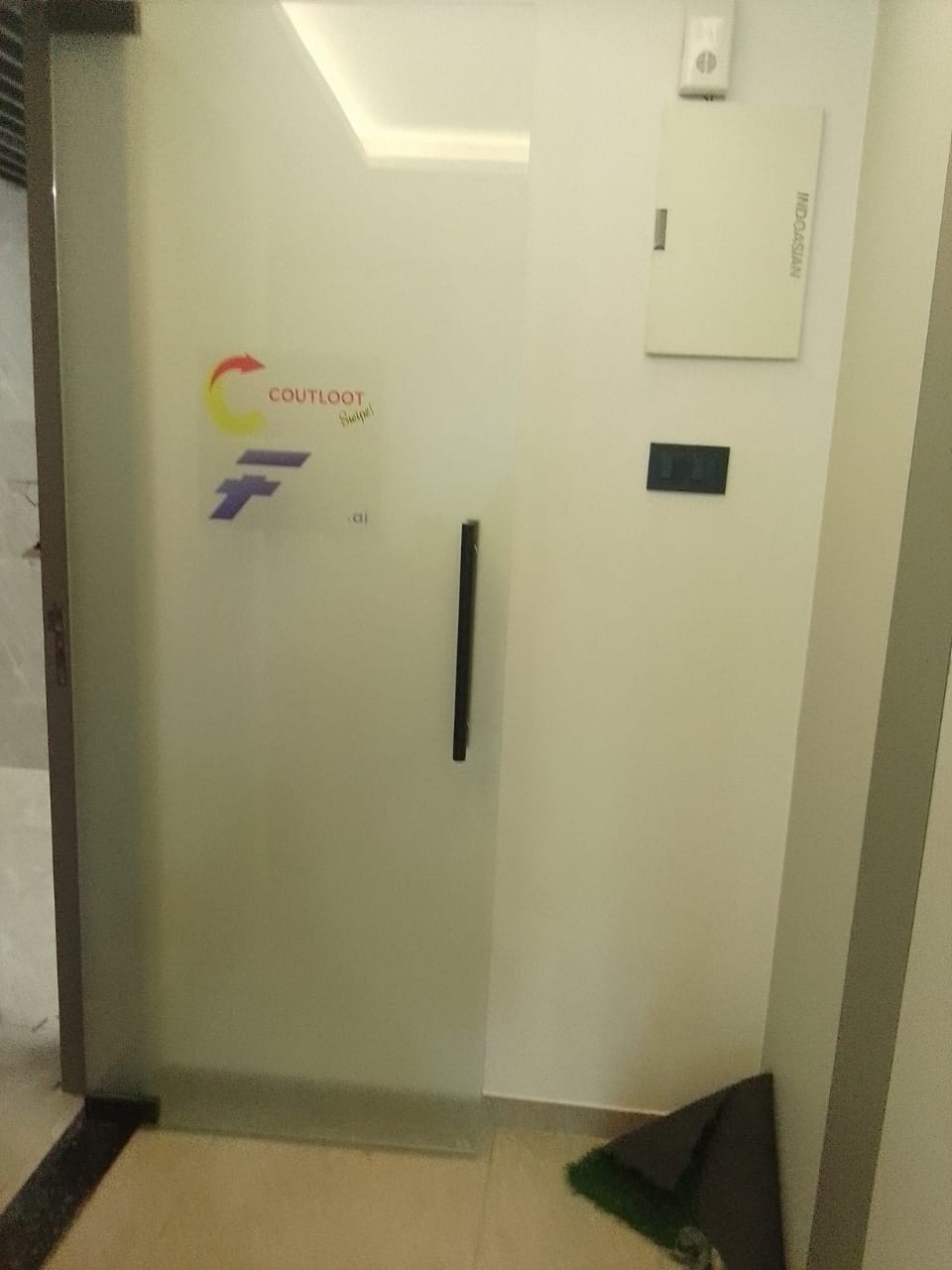 Frosted glass office door with a colour company logo decal applied at eye level beside a black bar handle