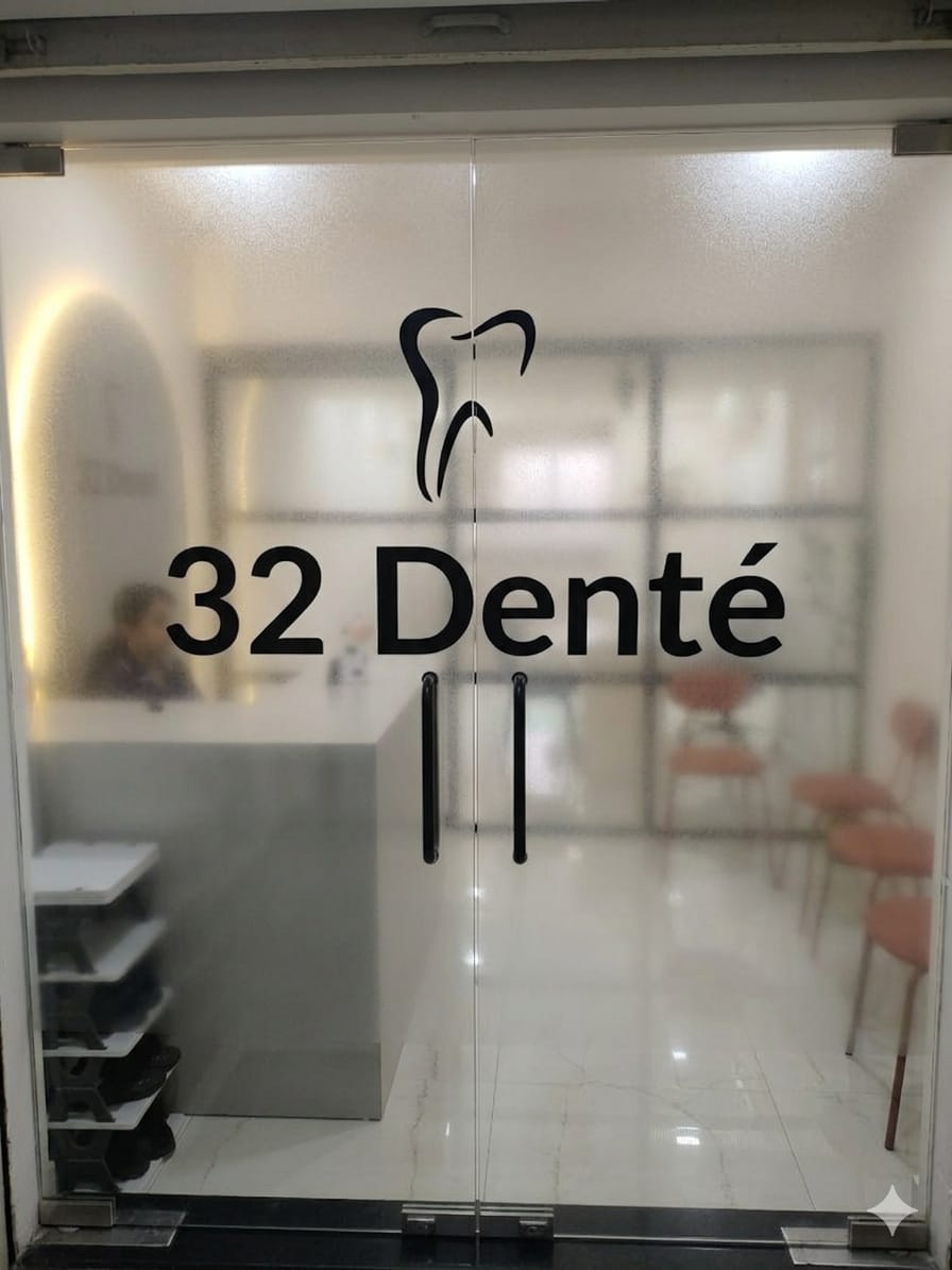 Frameless glass double doors of a dental clinic with a frosted upper band, clear vision strip and black vinyl logo