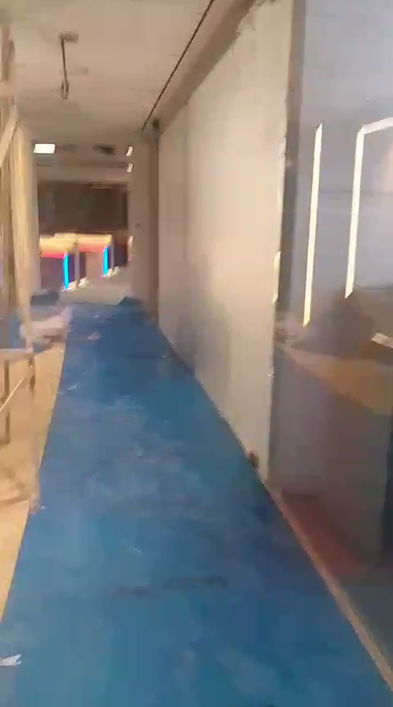 Video walking a commercial fit-out corridor lined with frosted glass partitions over blue floor protection