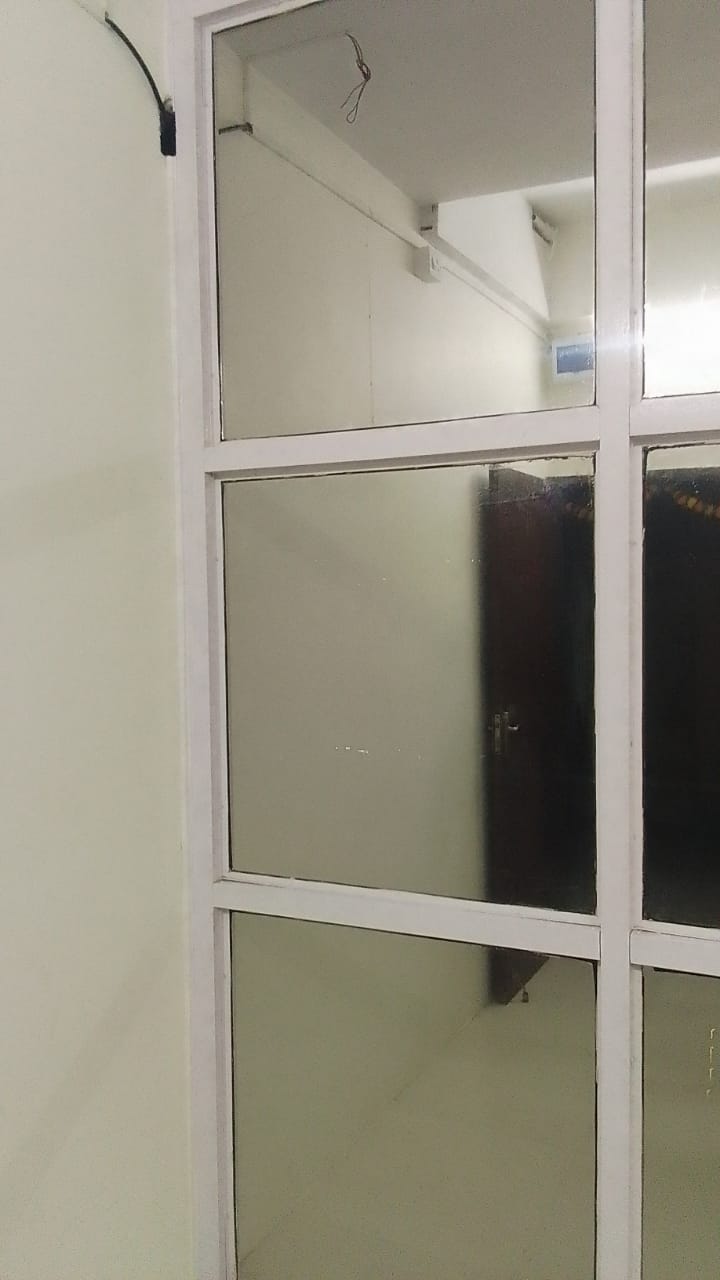 Frosted film on the panes of a white-framed internal glass partition, dark doorway visible through an untreated pane