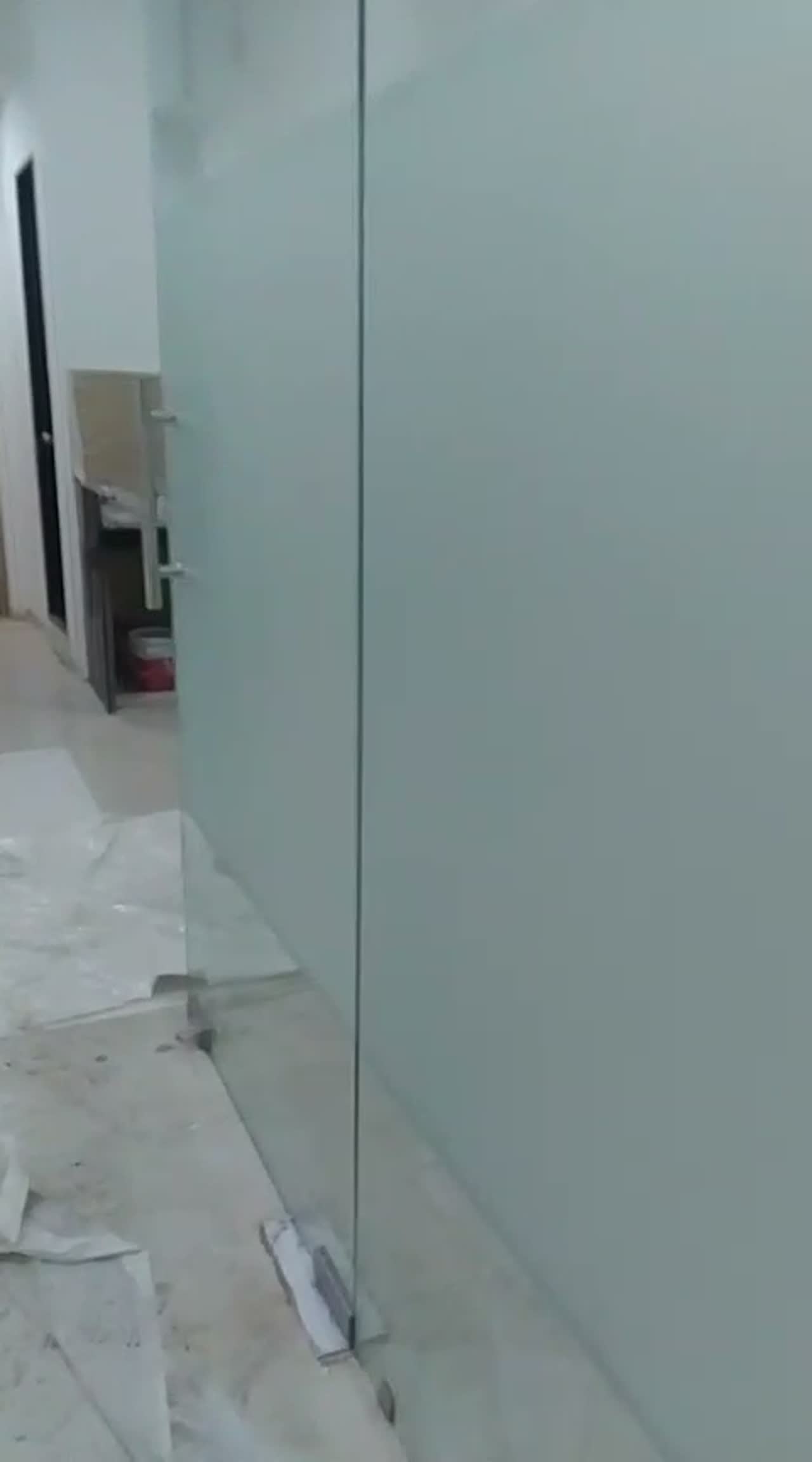 Video of a frosted glass partition and door in an office corridor during fit-out, protective sheeting on the floor