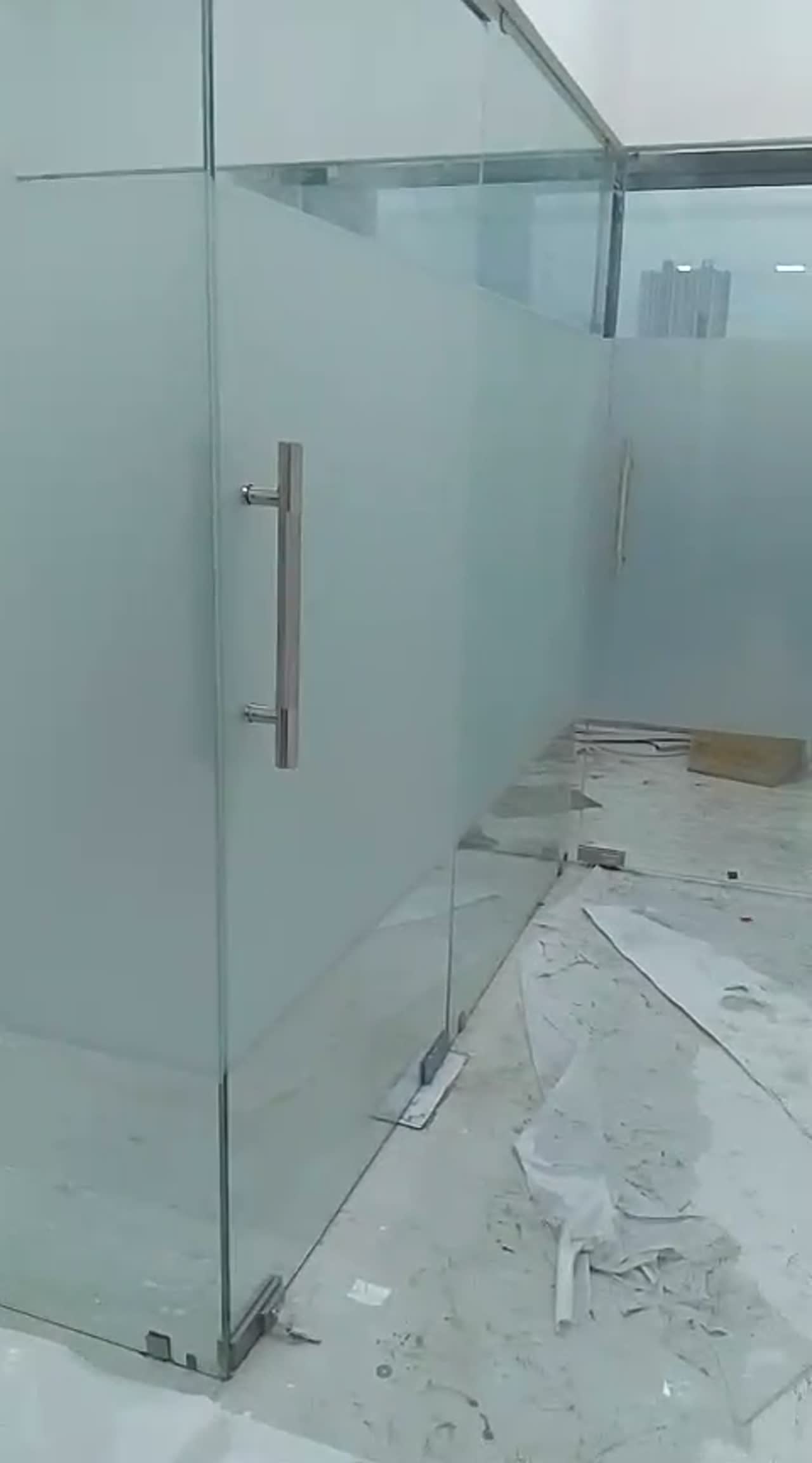 Video of a frosted glass partition and door with steel ladder handles on an unfinished concrete floor