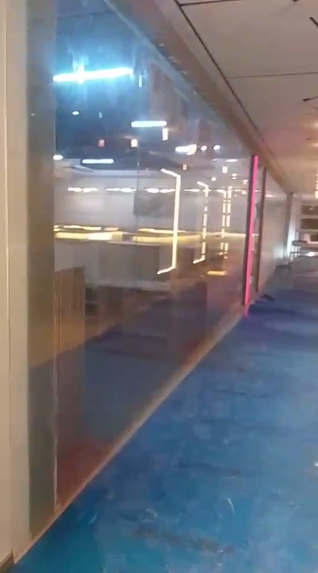 Video of a clear glass partition wall in a retail fit-out reflecting neon trims and display counters