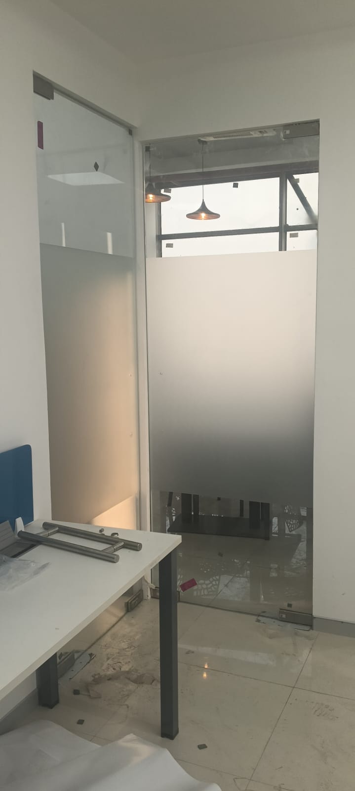 Gradient frosted film fading from opaque to clear on a tall office partition next to a frameless glass door