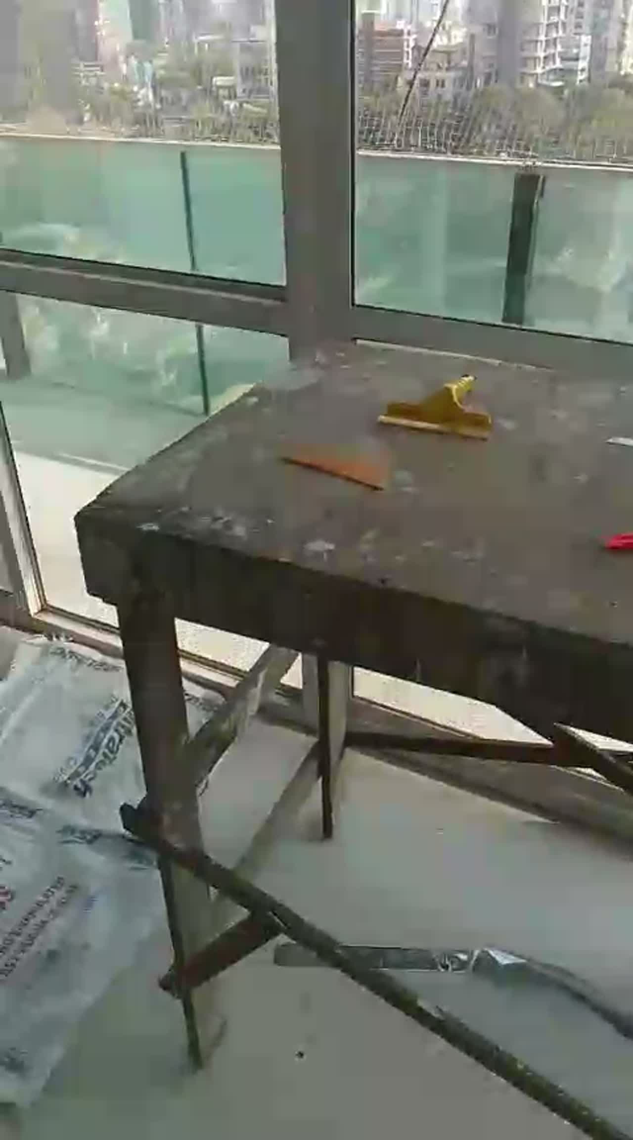 Video of a film cutting table with squeegee and blade set up beside high-rise perimeter glazing and a glass balcony