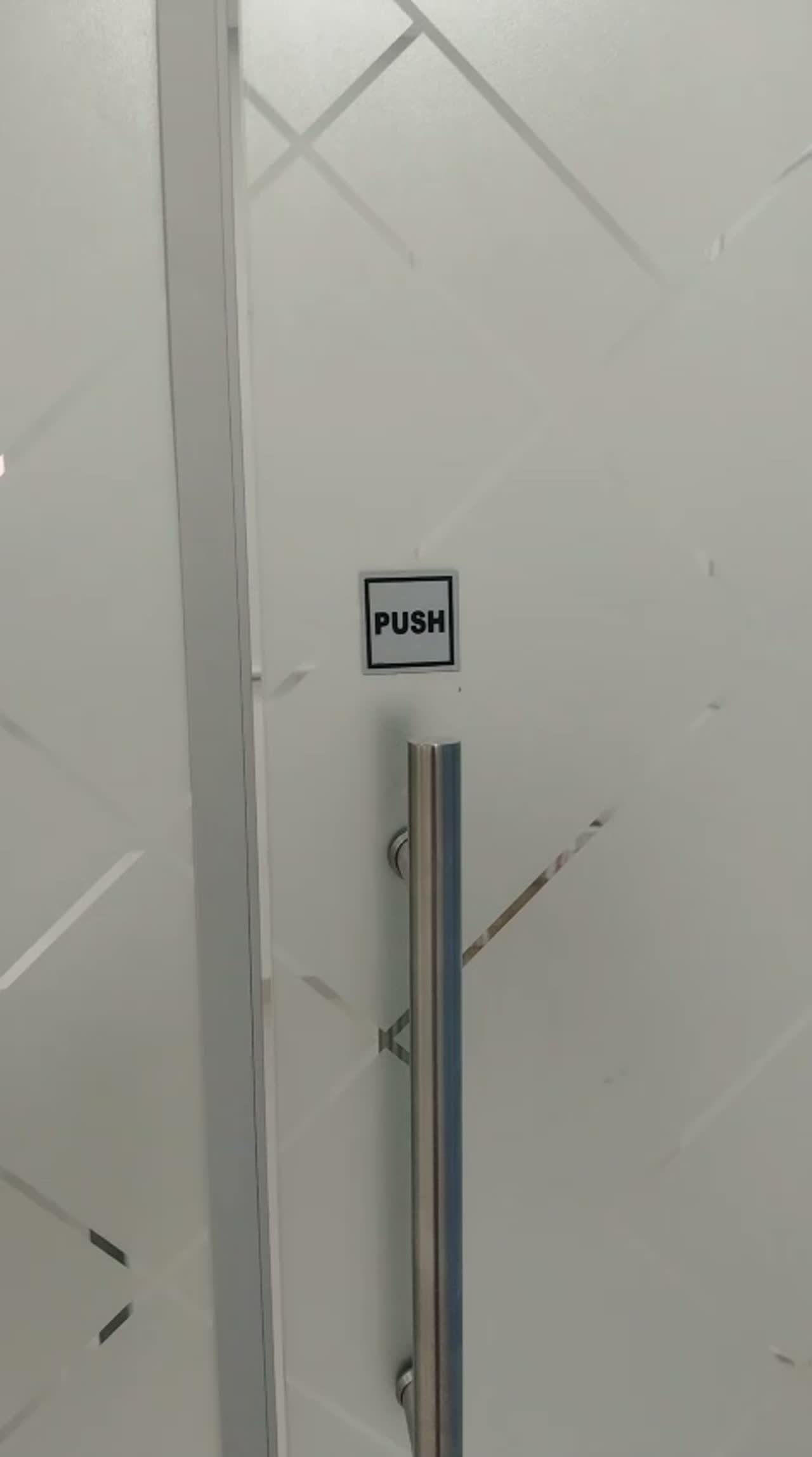 Close video of diamond lattice frosted film beside a steel door handle and PUSH sign