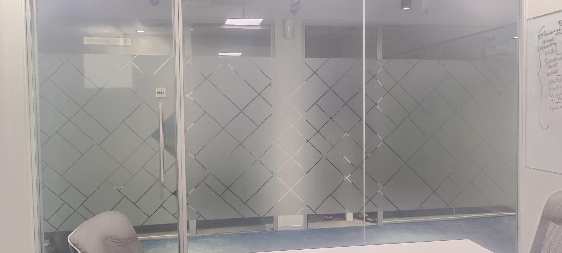 Frosted film with a diamond lattice pattern on a meeting room glass partition, chairs and whiteboard visible