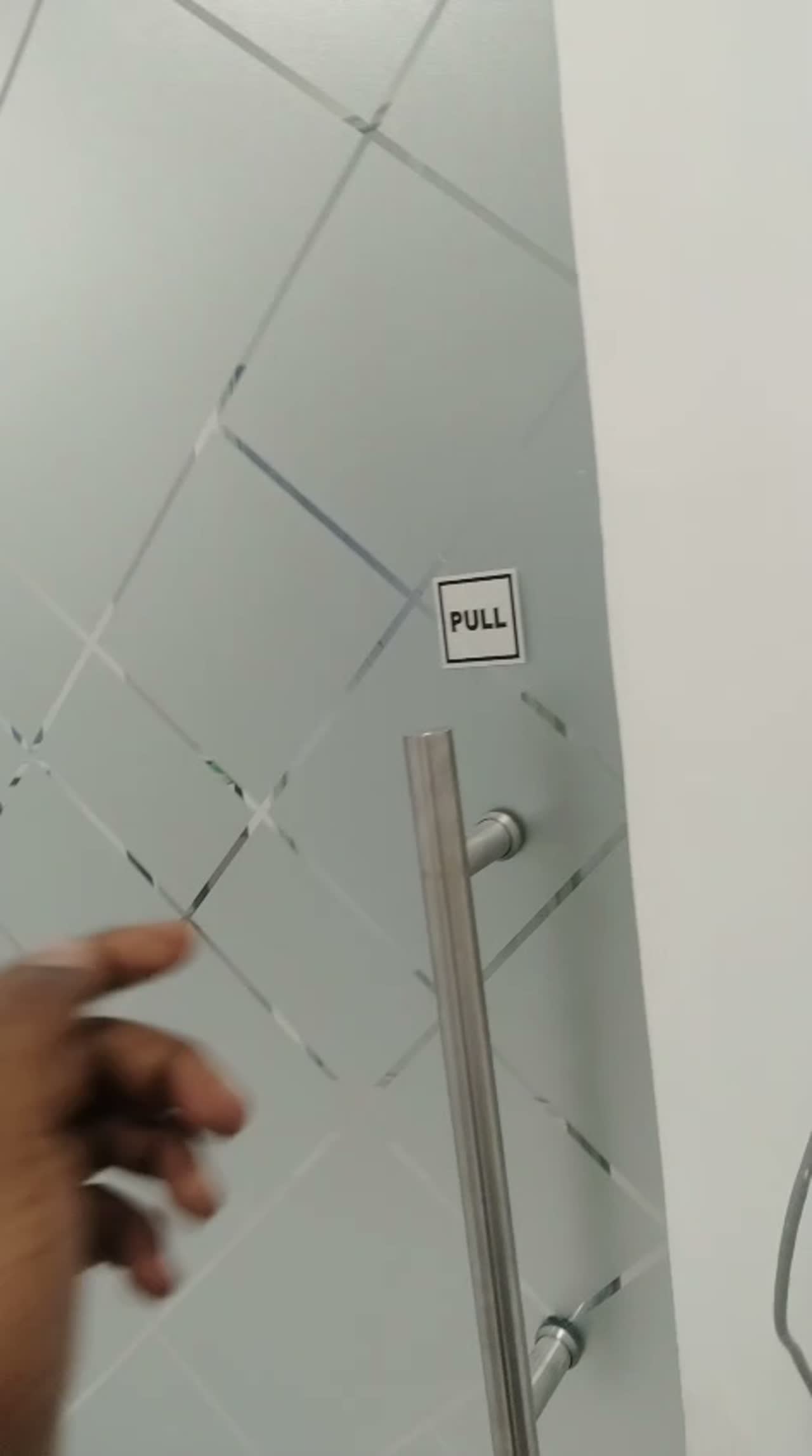 Video of a frosted glass office door with diamond lattice pattern and a PULL sign above the steel handle