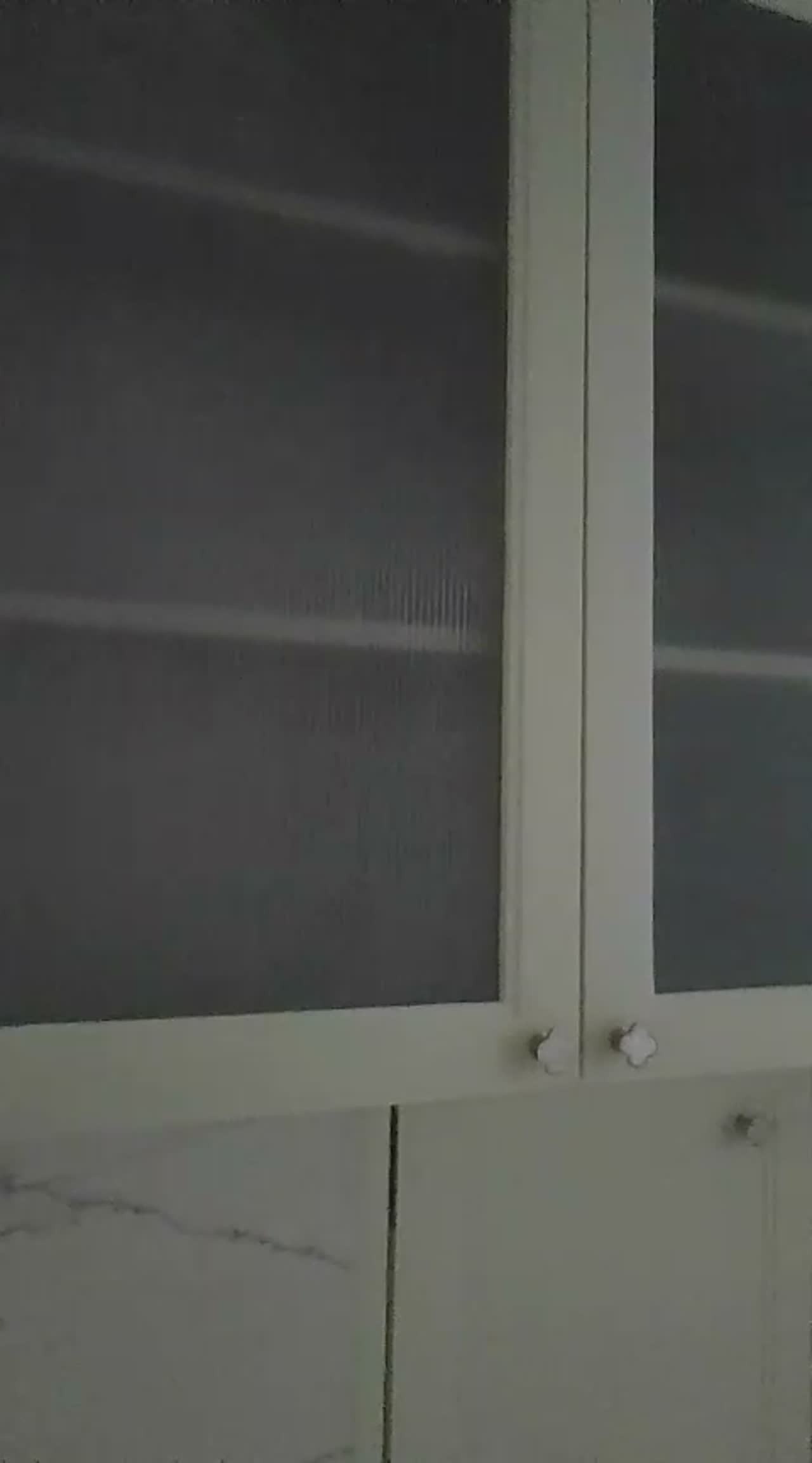 Reeded film applied to the glazed doors of a white kitchen crockery unit above a marble counter