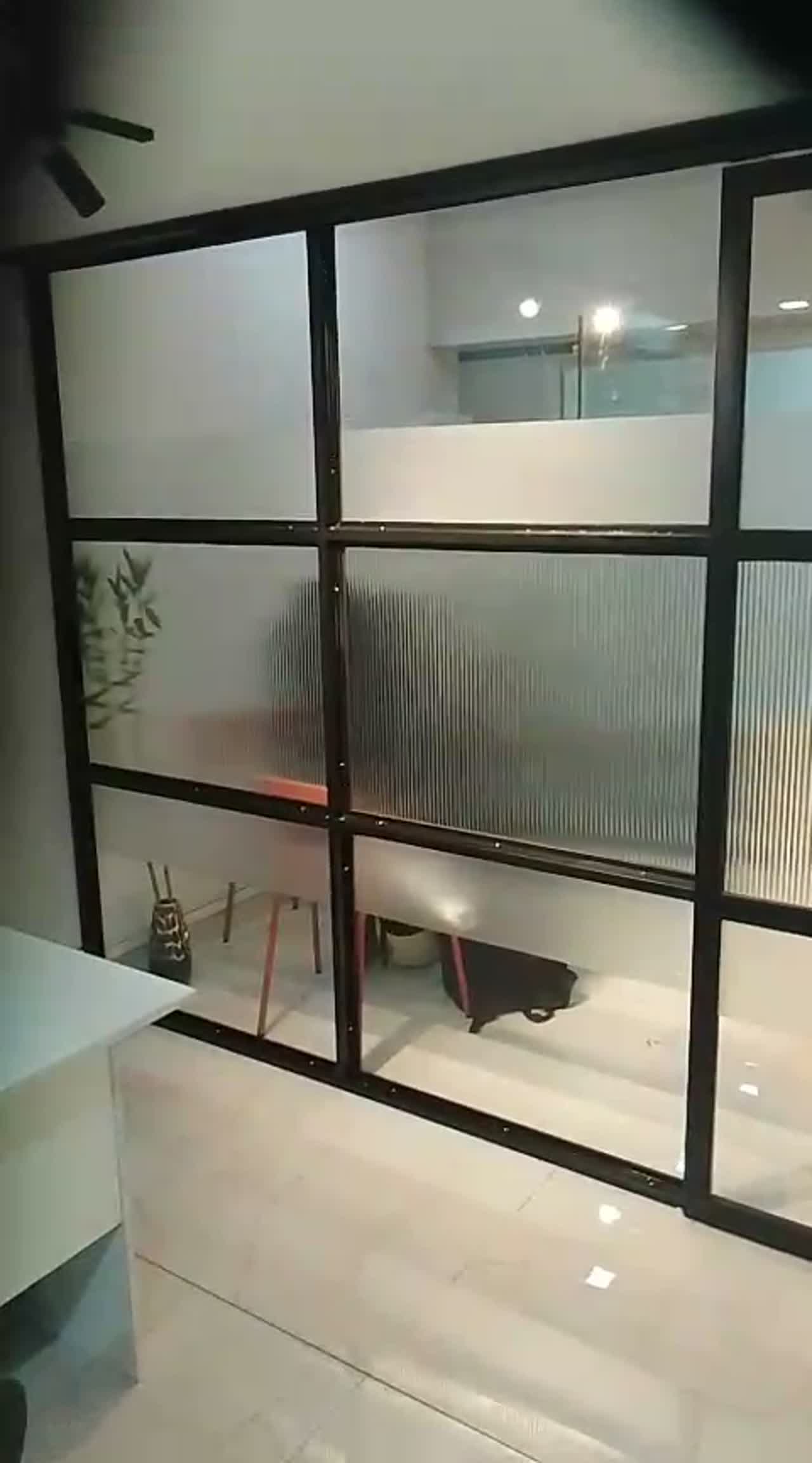 Video panning across a black-framed clinic partition with reeded panes and a clear upper row