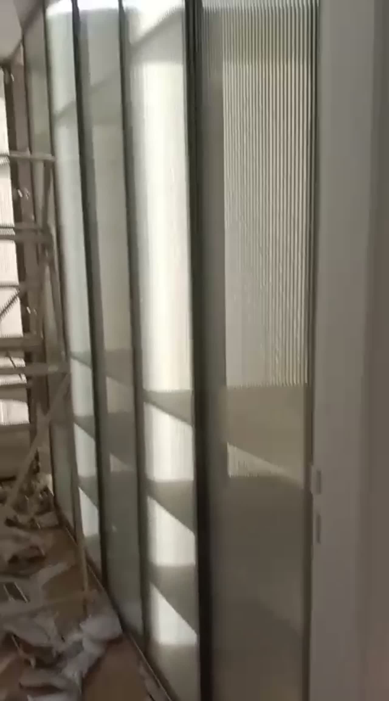 Video walking past a run of reeded film panels in a slim-framed partition on an unfinished fit-out floor