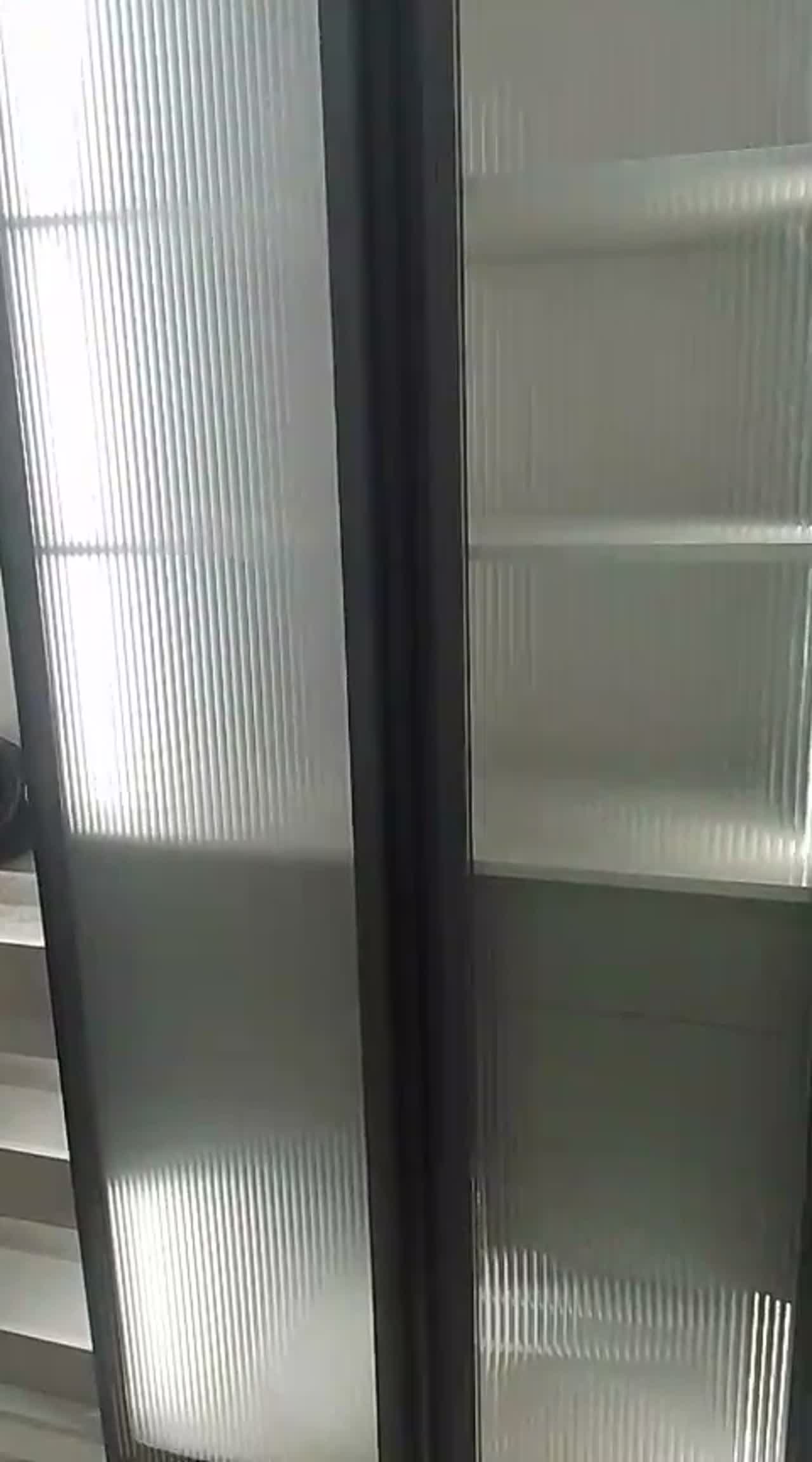 Close video pan across reeded translucent film on tall sliding glass doors with dark frames