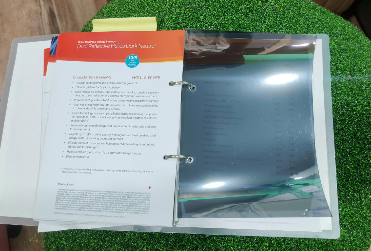 Open film sample binder showing a dual reflective solar film swatch beside its printed benefits sheet