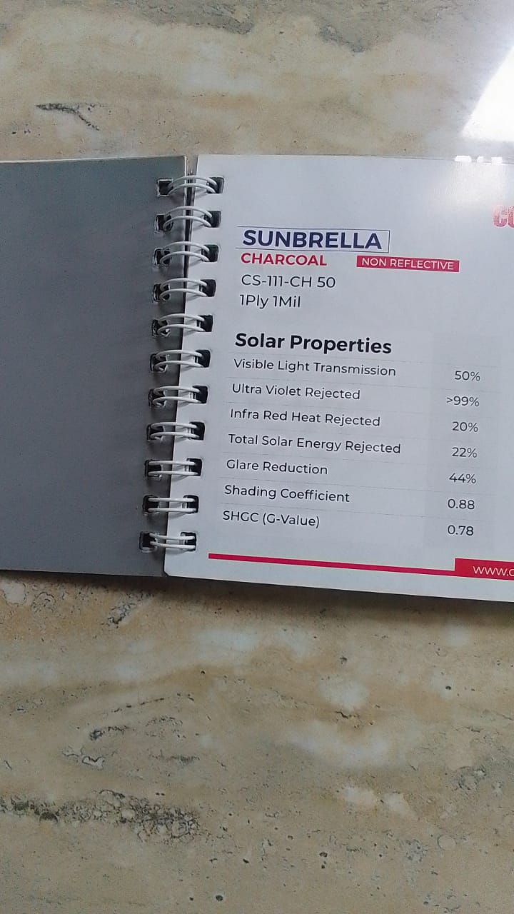 Film sample book open to a charcoal non-reflective solar film page listing 50 percent light transmission and over 99 percent UV rejection
