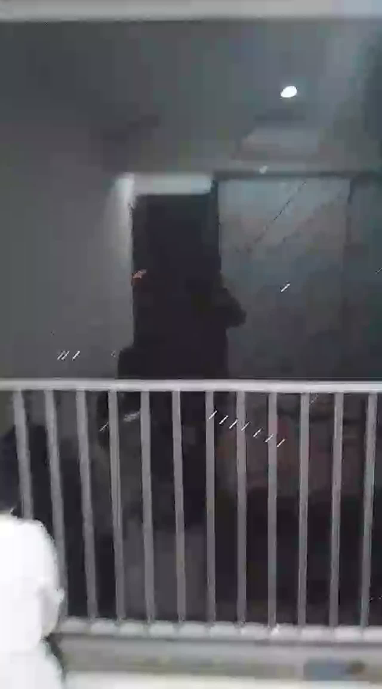 Night video of an installer finishing solar film on a bedroom balcony sliding door in a high-rise flat