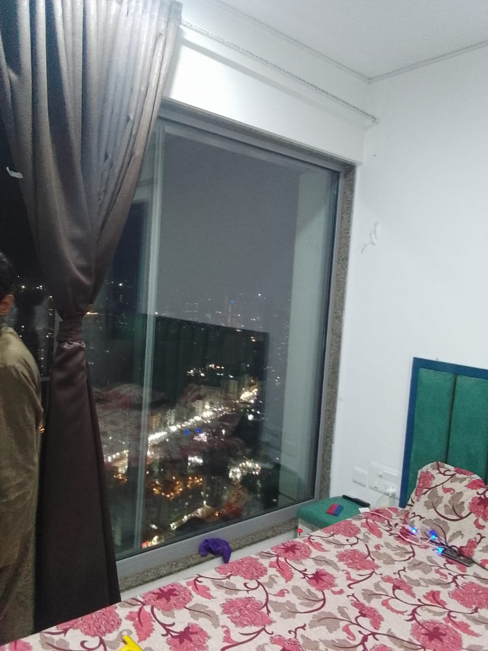 Tinted sliding bedroom window in a high-rise flat at night, city lights visible through the darkened glass