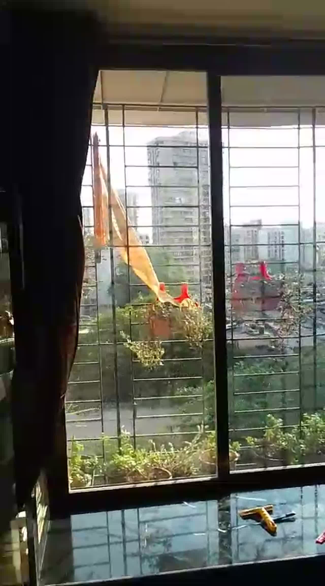 Video panning across sliding windows of a high-rise flat during solar film installation, tools resting on the window sill